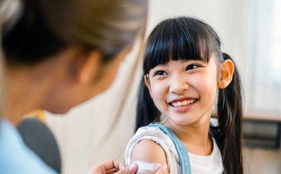 Chica recibiendo la vacuna contra la gripe y sonriendo