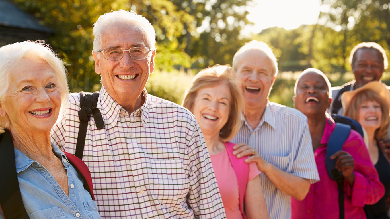 Grupo de personas mayores sonriendo afuera bajo el sol