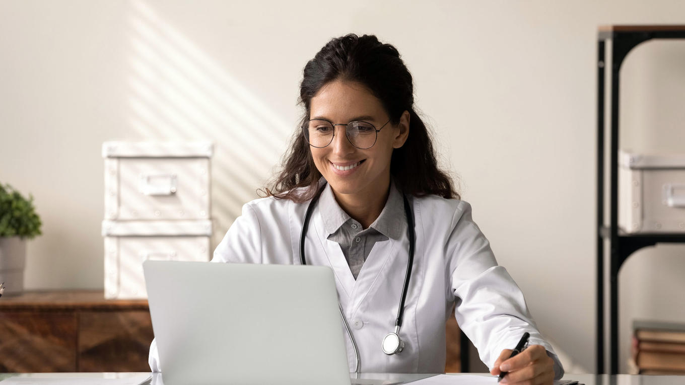 Doctor mirando su computadora portátil y sonriendo