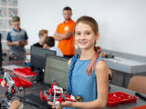 Chica en clase de ciencias, sosteniendo un robot Lego